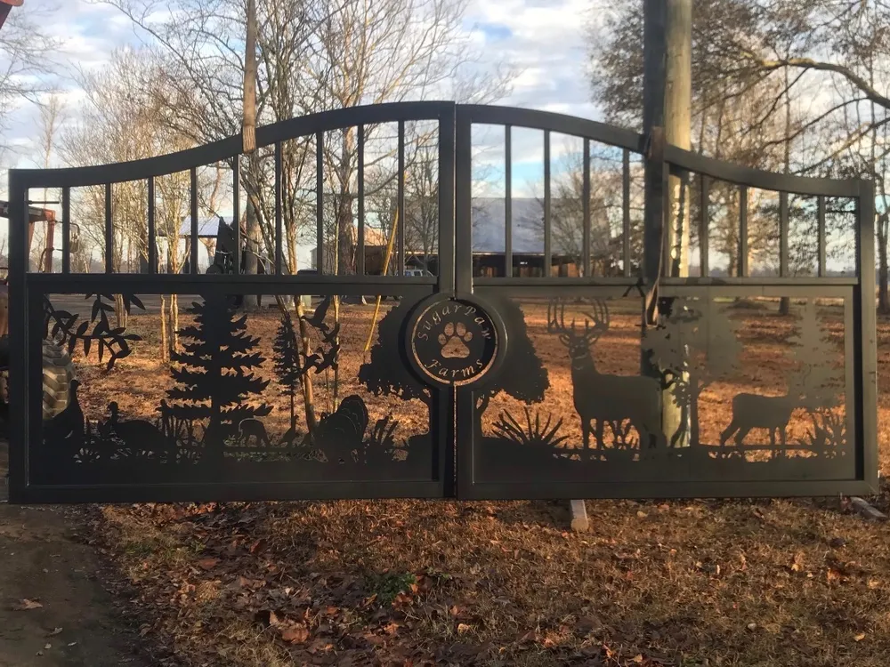 The Tennessee Deer Gate shut across a field entrance in low sun, bare trees and a metal barn showing through the cut woodland scene, with a utility pole standing in front of the right leaf.