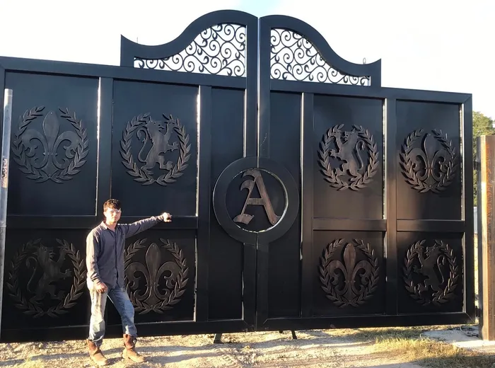 The pair standing in the yard before installation, low sun raking across the wreath medallions and the split ring at the centre, with a man at the left leaf for scale.