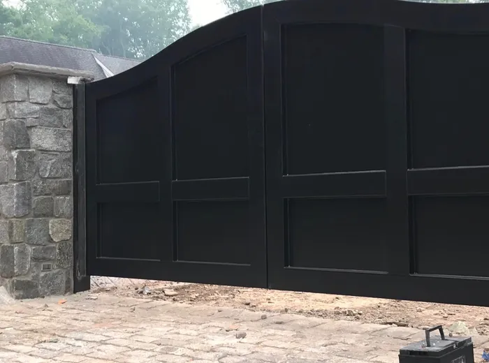 The Tappan Gate seen along its length from beside the left pier, the top rail sweeping up out of the post and the raised frames standing off each panel.