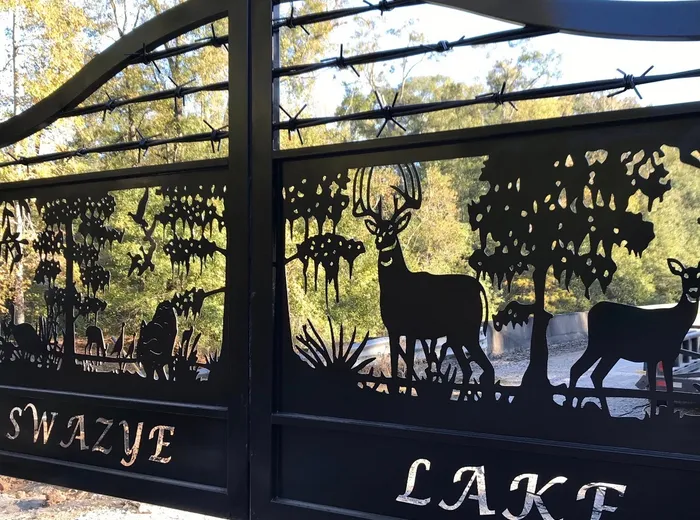 Close oblique view of the cut panels, a buck and a doe standing beneath a hardwood canopy with barbed-wire strands crossing the arch above and cut lettering along the bottom band.