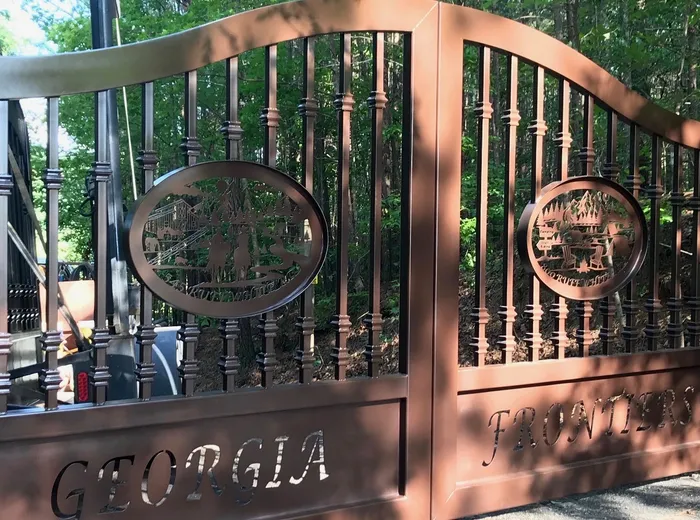 A second build of the design in a warm copper tone, its oval medallion cut with a cabin-and-pines scene and lettering cut through the bottom panel.