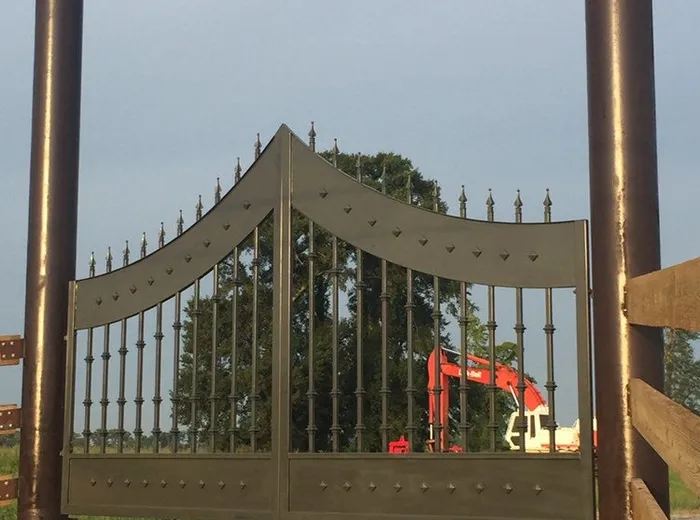 The Disotell Gate closed square-on between both pipe posts against open sky and treeline.