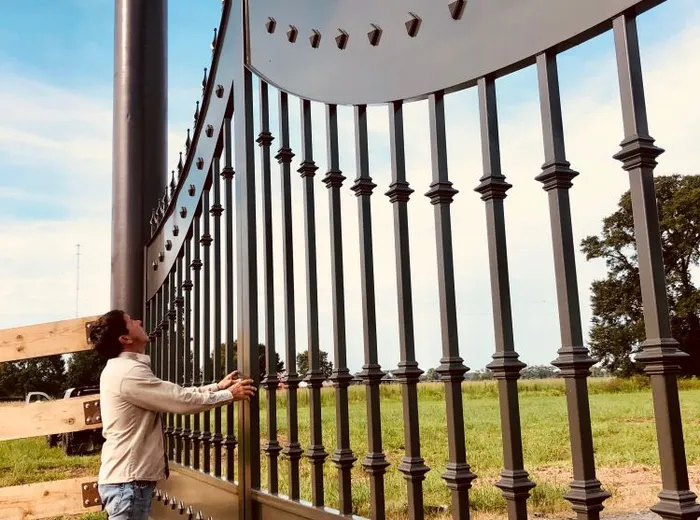 A person standing beside the installed Disotell Gate, showing it reaching well above head height.