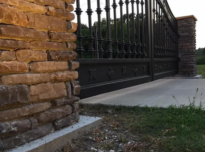 The gate's lower rail and baluster feet where they meet the concrete drive.