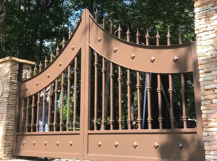 A light brown build of the Disotell Gate square-on, both top rails sweeping up to a peak at the centre, diamond studs banded across the curve and the solid lower panel.